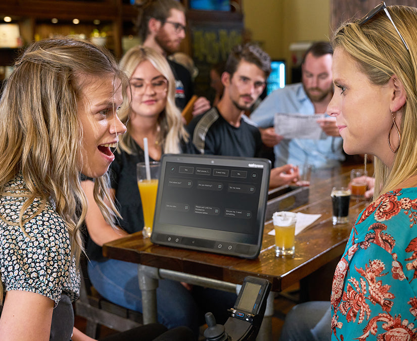 Tobii Dynavox TD Talk vist på en TD I-Series af Delaina som taler med sin ven i en bar